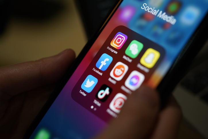 person holding a phone screen displaying social media fundraising app icons
