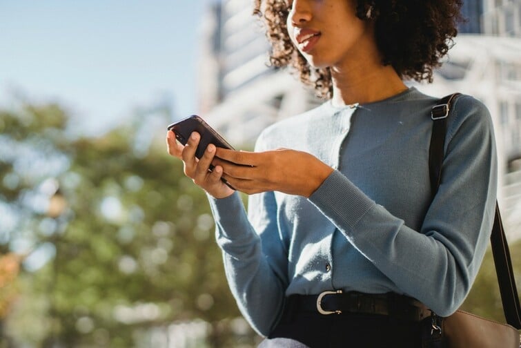 woman standing outside looking at her phone