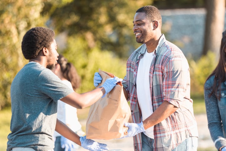 man giving a bag of food to another man at a food drive