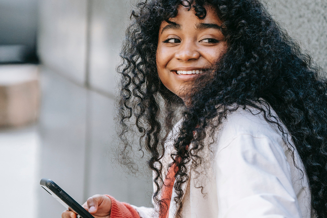 woman smiling while holding a phone