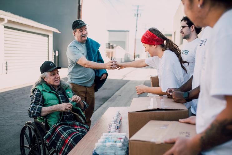 volunteers passing out water bottles outdoors at a shelter