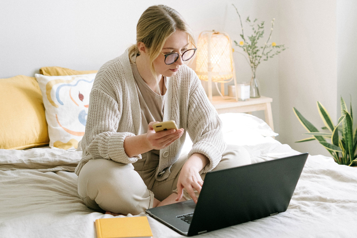 woman using technology while sitting on her bed