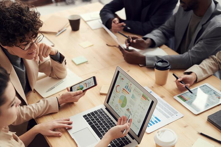 people working around a table on their phones and computers