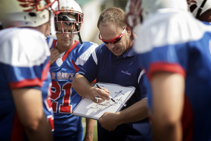 football coach drawing up a play on a whiteboard