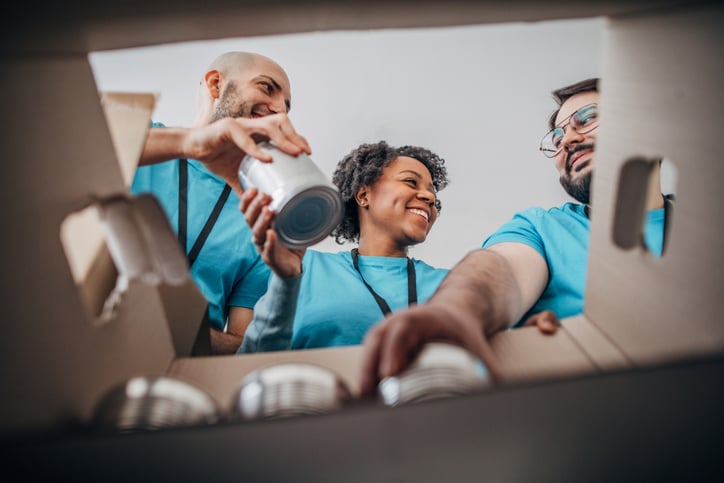 three people helping load canned foods into a box