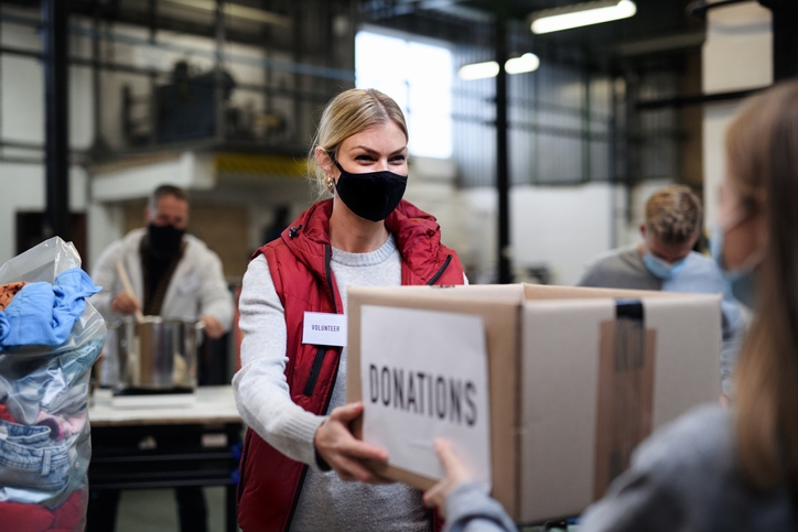 woman being given box of clothes and noncash donations