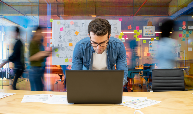 man leaning over a computer writing a noncash appeal email in an office