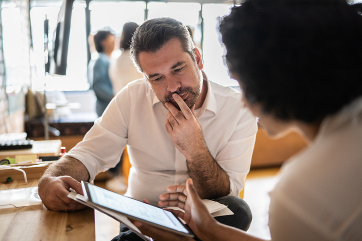 man looking at a tablet while talking with a coworker about ab testing for nonprofits