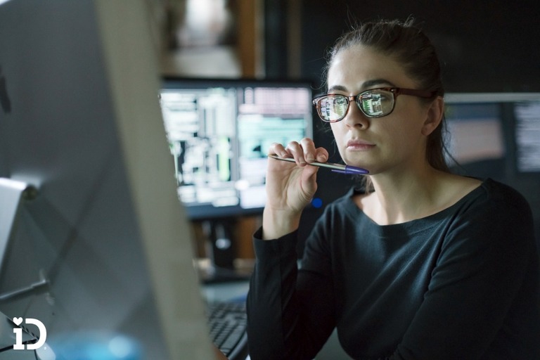 woman in glasses studying data on a computer