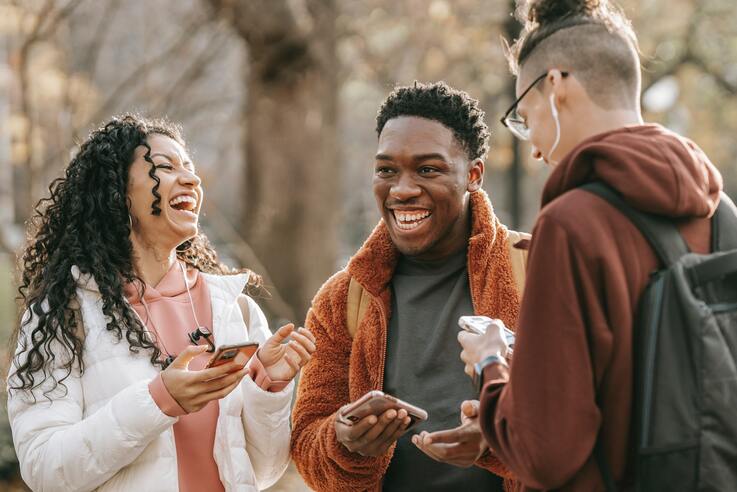 three friends talking and laughing together in a park